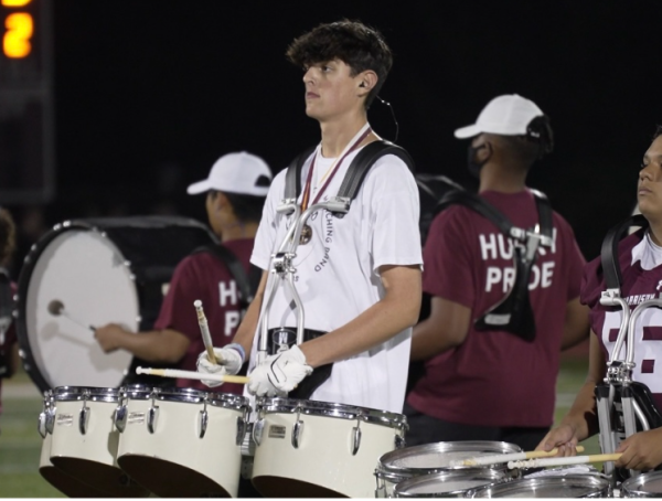 Oliver playing drums during a halftime performance at a Harrison High School football game